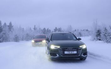 Zwei Autos fahren auf einer Schneefahrbahn. Winterliche und verschneite Bäume und Hintergrund.