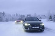 Zwei Autos fahren auf einer Schneefahrbahn. Winterliche und verschneite Bäume und Hintergrund.