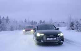 Zwei Autos fahren auf einer Schneefahrbahn. Winterliche und verschneite Bäume und Hintergrund.