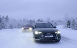 Zwei Autos fahren auf einer Schneefahrbahn. Winterliche und verschneite Bäume und Hintergrund.