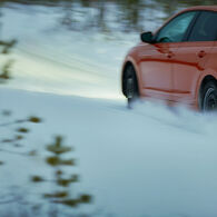 Ein rotes Auto auf winterlicher, verschneiter Fahrbahn