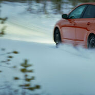 Ein rotes Auto auf winterlicher, verschneiter Fahrbahn