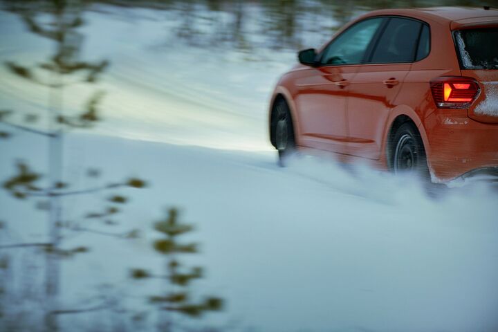 Ein rotes Auto auf winterlicher, verschneiter Fahrbahn