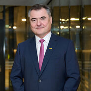 Porträtfoto von ÖAMTC-Präsident Markus Ludvik im Anzug vor einer Glasfassade