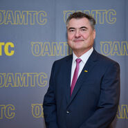 Porträtfoto von ÖAMTC-Präsident Markus Ludvik im Anzug vor einer Leinwand mit ÖAMTC-Schriftzügen