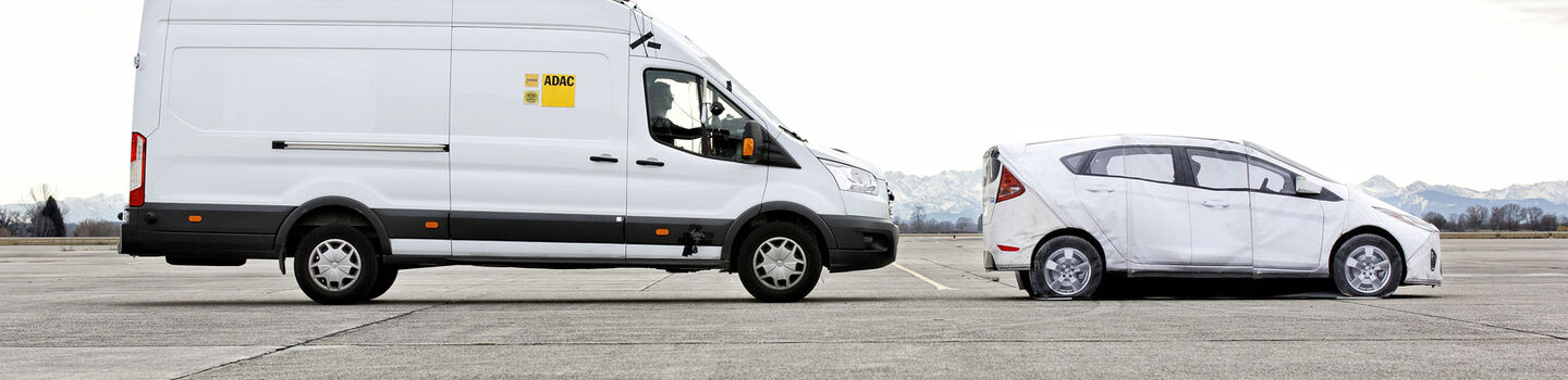 Klein-Lkw steht bzw. bremst hinter Auto auf einer Asphaltstraße.