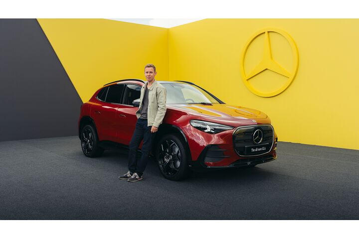 Ein Mann lehnt an einem roten Mercedes-SUV.