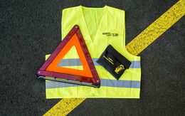 Auf einer Straße liegt eine Warnweste, ein Pannendreieck, eine Motorradapotheke.