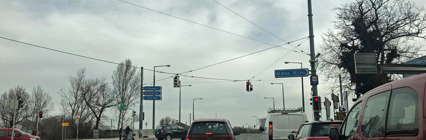 Autos vor einer roten Ampel in einem Baustellenbereich vor einer Brücke