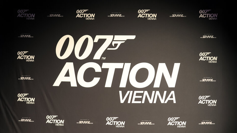 Plakat von der 007 Action Vienna Ausstellung, weiße Schrift auf schwarzem Hintergrund. 