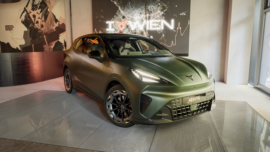 Front eines grau-grünen Cupra Raval, der in einer großen Fensterauslage steht.