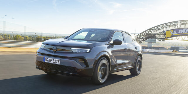 Opel Mokka GSE von vorne, leicht seitlich, bei der Fahrt. Er ist auf der Rennstrecke. Das Wetter ist schön.