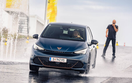Ein blauer Cupra Born fährt über eine nasse Trainingsfläche