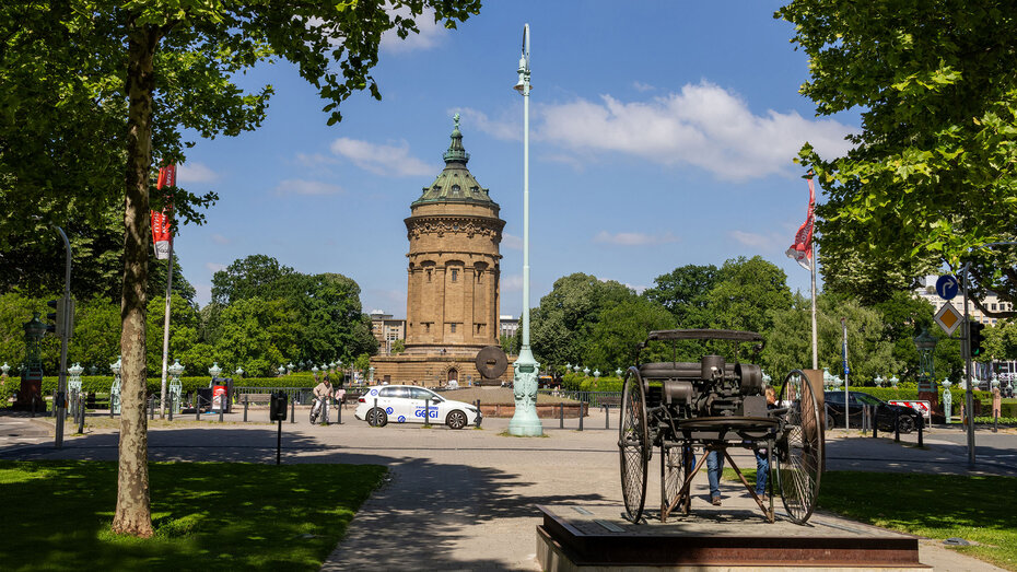 Wahrzeichen Mannheimer Wasserturm – davor die Bronze-Nachbildung des Motordreirads von Carl Benz