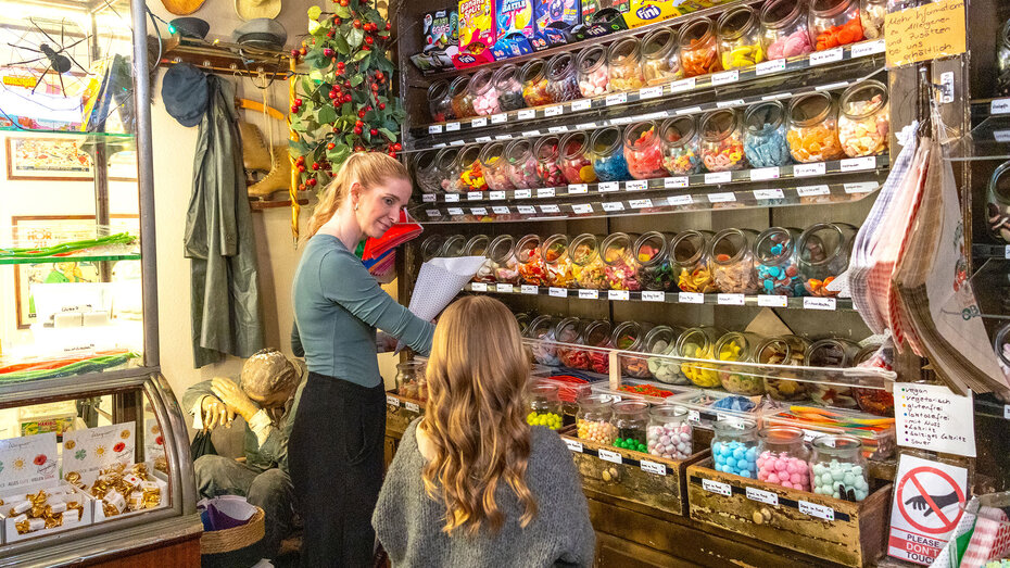 Verkäuferin füllt für ein Kind ein Papierstanitzel mit Süßigkeiten im Heidelberger Zuckerladen