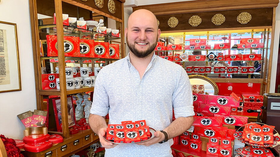 Verkaufer mit Studentenkuss-Schokotalern auf deinem Tablett steht im der Chocolaterie.