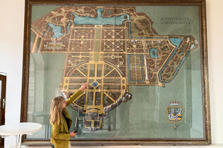REiseleiterin vor einem übergroßen Plan des Barock-Schlossgartens in Schwetzingen
