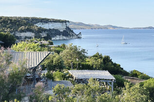 Blick auf die Küste, ein paar Häuser und das Meer. 