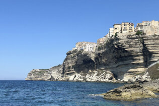 Imposante Felsen am Meer und oben thront eine kleine Stadt. 