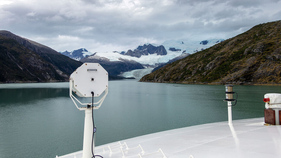 Blick über den Bug der Stella Australis in den Pia-Fjord mit tief hängenden Wolken