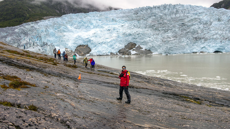 Passagiere wandern über glatte Felsen zur Front des Pia-Gleschers