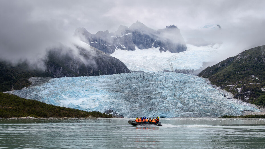 Zodiac fährt Richtung Pia-Gletscher, dahinter hängen Wolken 