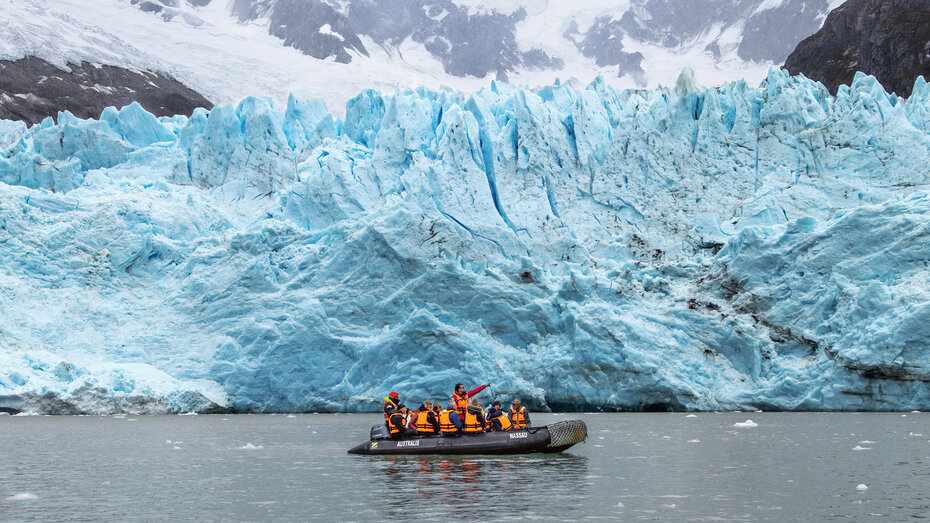 Zodiac mit Passagieren mit orangen Schwimmwesten vor dem türkis-blau-weißen Porter-Gletscher