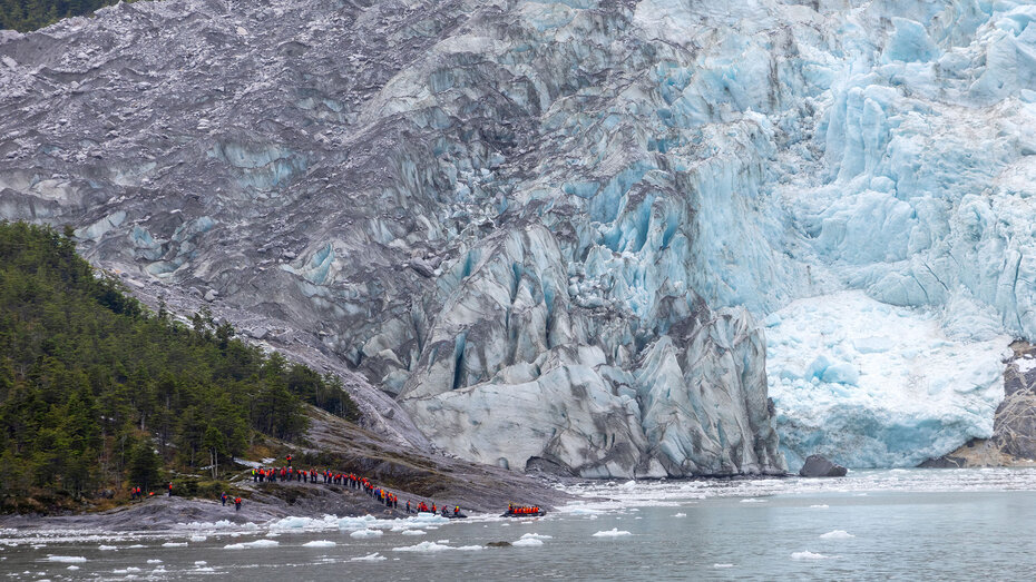 Von der Ferne vom Schiff aus fotografiert: Passagiere warten vor der Eisfront des Pia-Gletschers auf die Abholung mit den Zodiacs.