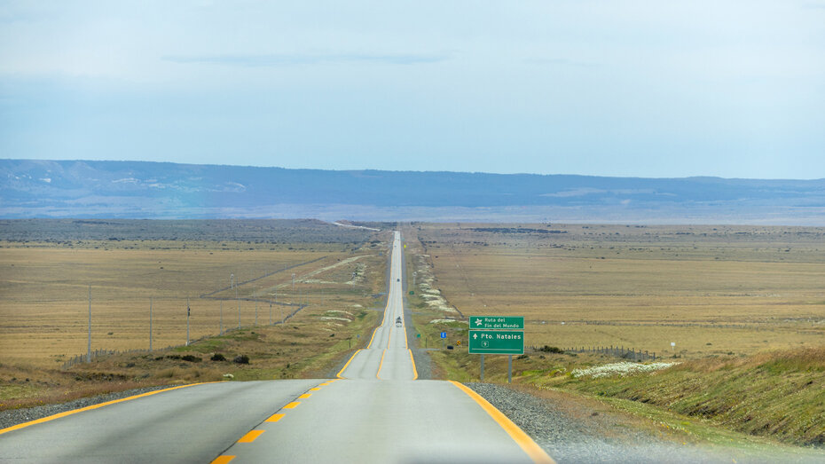 Straße Ruta 9 geradeaus durch die braune Pampa. In der Ferne eine niedrige Hügelkette.
