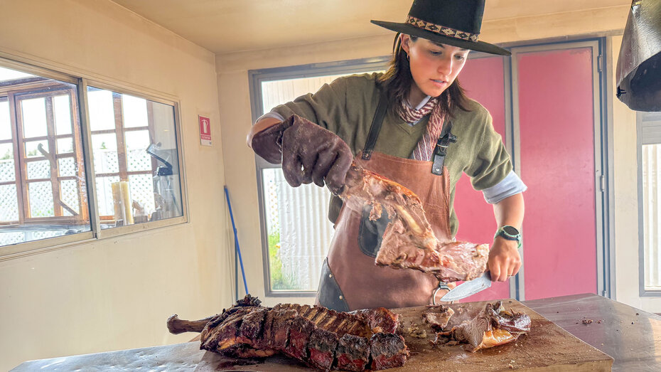Junge Dame auf Estancia zerlegt das Lamm vom Asador-Grill