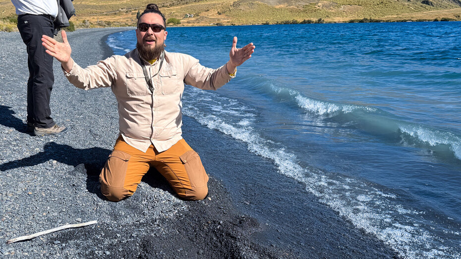 Guide Collins kniet im scharzen Lavasand am Ufer der Laguna Azul und formt anschaulich die Entstehung der Anden