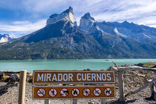 Blick vom Aussichtspunkt auf den grünen Nordenskjöld-See, dahineter die bizarren Berge Cueernos del Paine, vorne das Schild mit Aufschrift Mirador Cuernos