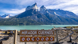 Blick vom Aussichtspunkt auf den grünen Nordenskjöld-See, dahineter die bizarren Berge Cueernos del Paine, vorne das Schild mit Aufschrift Mirador Cuernos