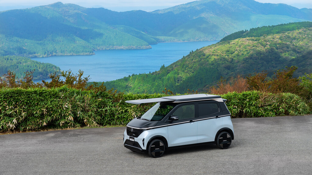 Ein Kei-Car mit Solarpanelen auf dem Dach vor einem Panorama