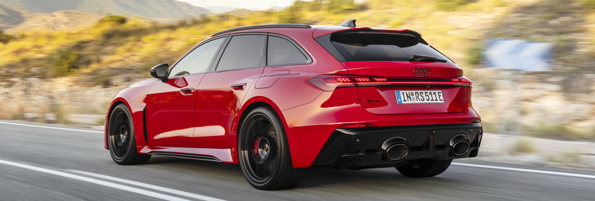 Ein roter Audi RS 5 Avant fährt durch eine Kurve einer Landstraße.