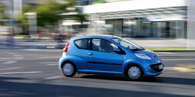 Ein blauer Kleinwagen fährt durch die Stadt