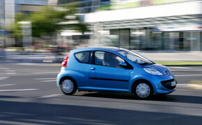 Ein blauer Kleinwagen fährt durch die Stadt