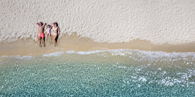 Familie am Strand liegen von oben