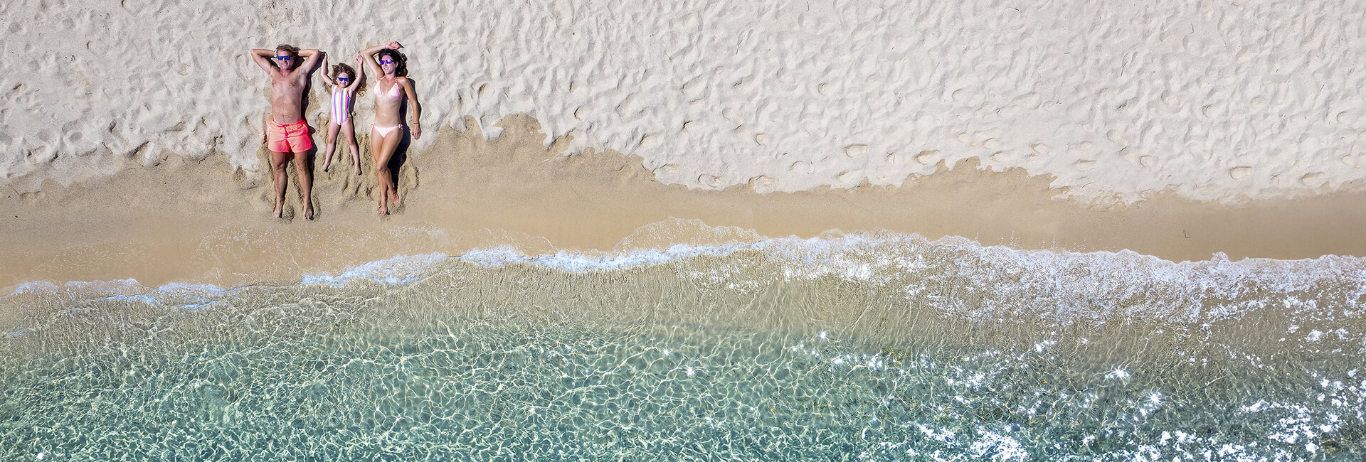 Familie am Strand liegen von oben