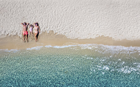 Familie am Strand liegen von oben