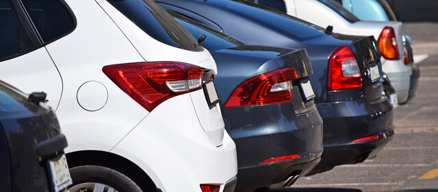 Die Hecks von mehreren nebeneinander stehenden Autos auf einem Parkplatz