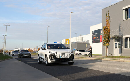Ein weißer Audi fährt an einem grauen Gebäude vorbei