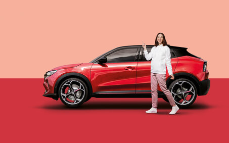 Eine Frau steht vor einem roten Auto