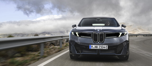 Ein dunkelgrauer BMW iX3 fährt auf einer Landstraße.