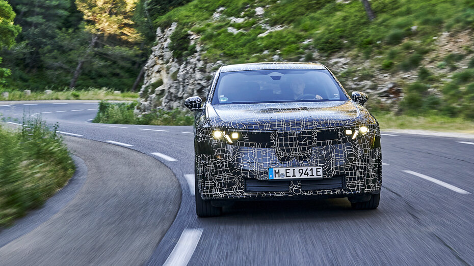 Ein getarntes BMW SUV fährt über eine Landstraße.