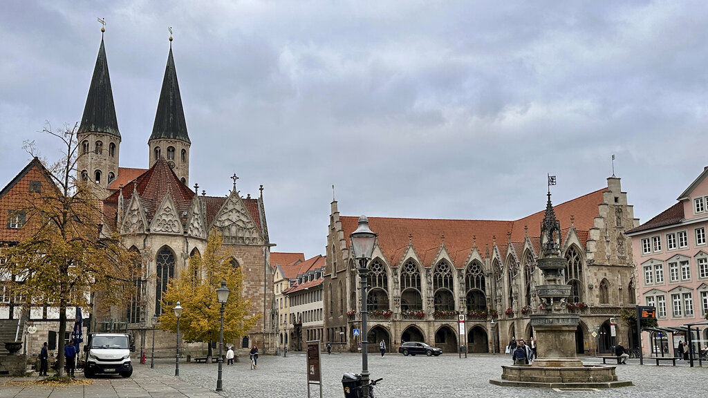 Ein großer Platz, links eine Kirche mit zwei Türmen, vorne ein Denkmal.