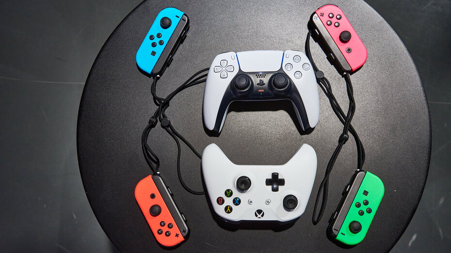 Ein Playstation, ein Xbox und 4 Switch Controller aufgelegt auf einem schwarzen Tisch.