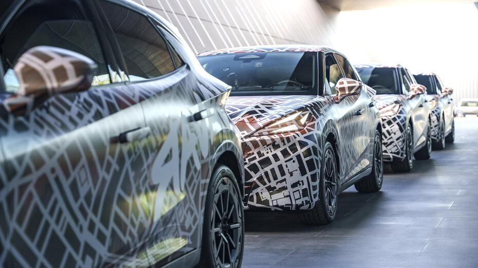 Mehrere mit Tarnfolie folierte Cupra Raval stehen hintereinander aufgereiht.