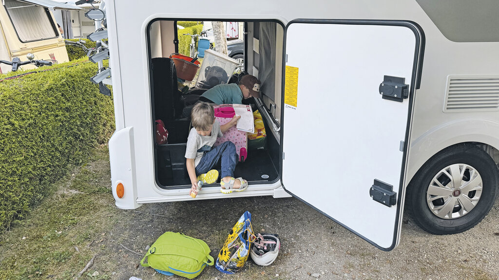 Die Jungs räumen aus der Heckgarage ihre Sachen heraus.