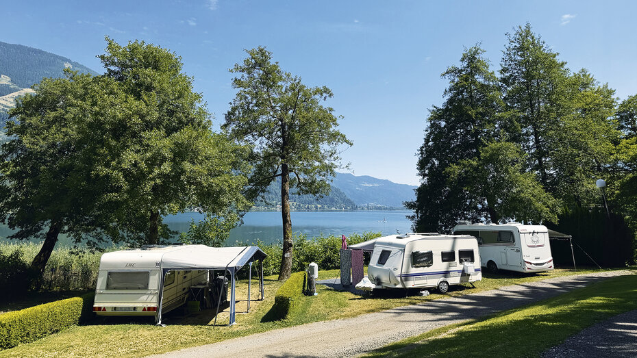 Blick auf ein paar Wohnwagen mit dem See im Hintergrund.